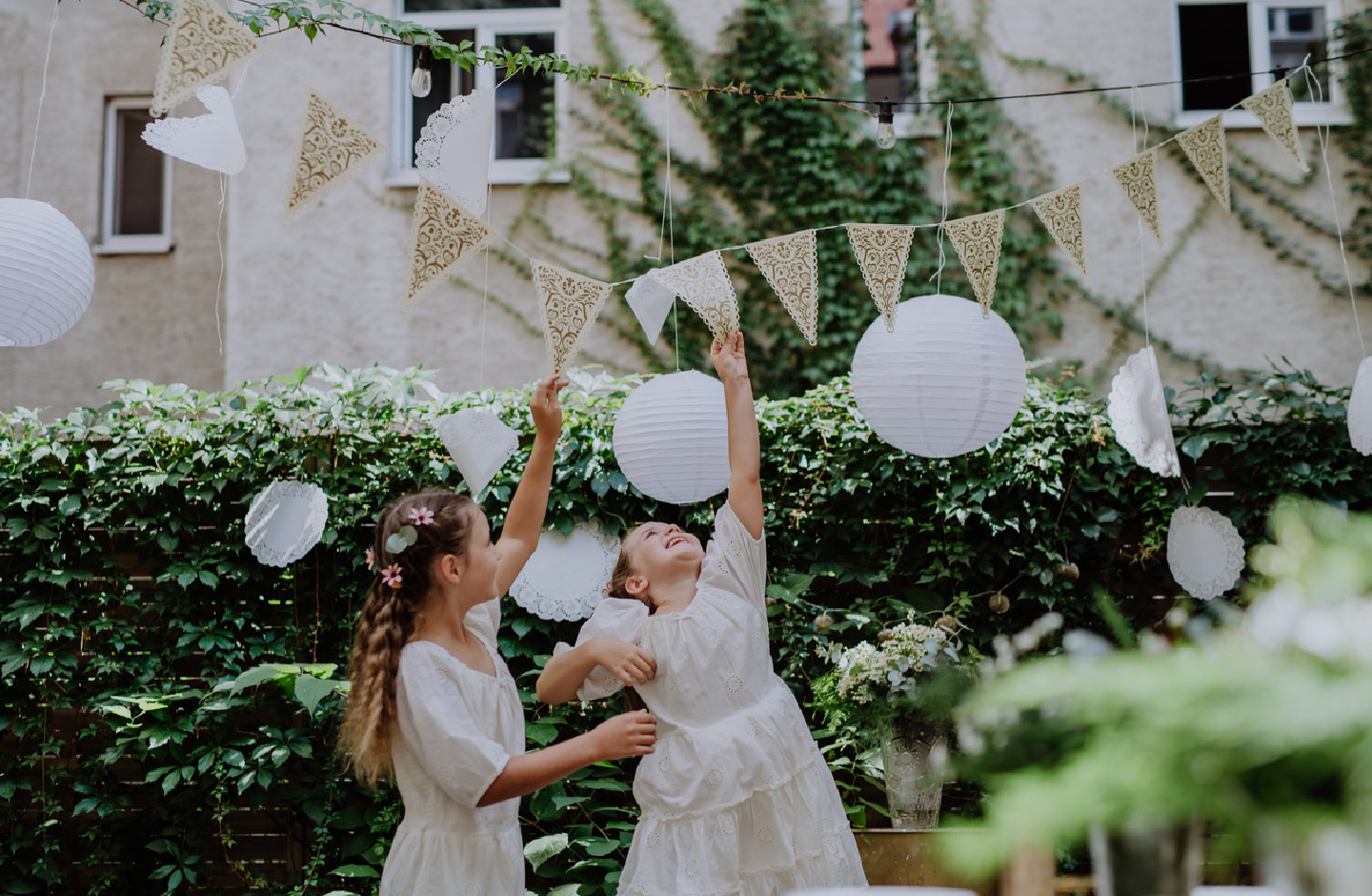 Kleine Mädchen spielen bei einer Hochzeit im Garten mit einer Girlande