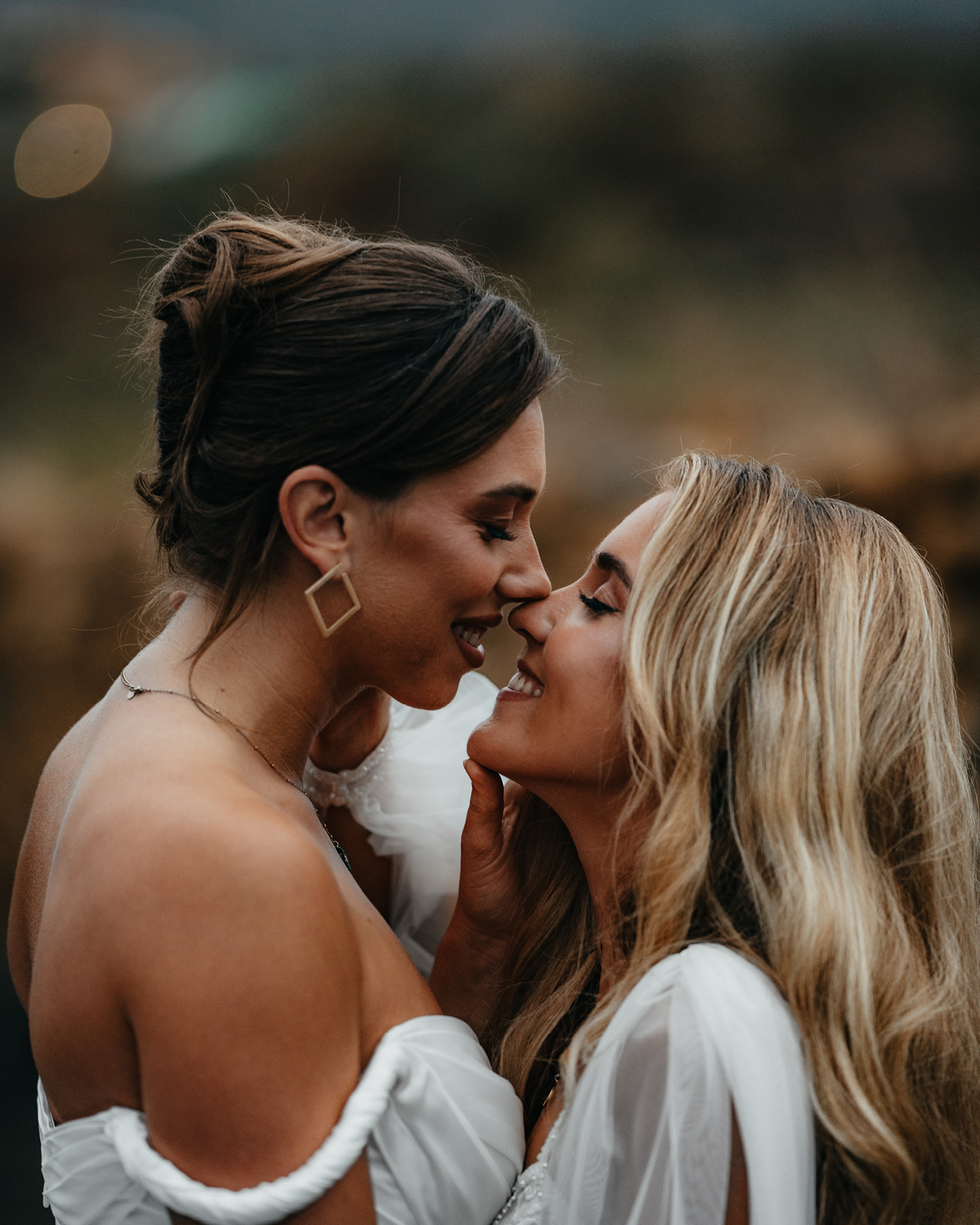 Gros plan de deux mariées dans une pose tendre, échangeant un regard doux et complice.